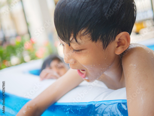 Two cute Asian children happily playing in an inflatable pool in summer. including jumping into the water, diving in the inflatable pond