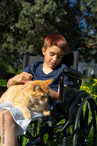 Physically disabled boy in a wheelchair with his cat outdoors © Arianne