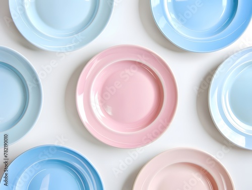 Arranged a lot of pastel coloured plates on white background