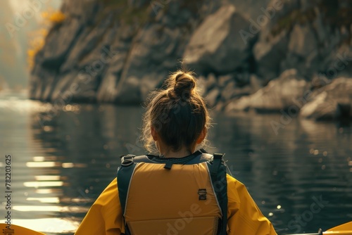 A woman in a yellow jacket paddling a yellow kayak. Suitable for outdoor and recreational themes