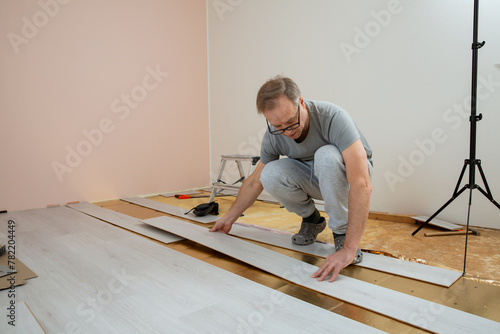 Two mature men installing laminate flooring in a new home together. DIY concept. Professional renovation of a house.