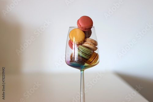 Champagne glass full of colorful macaroons on the table. Selective focus.