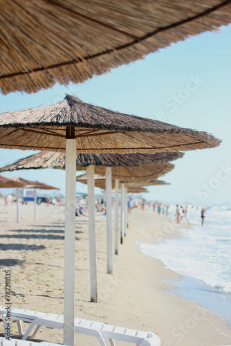 Fototapeta Naklejka Na Ścianę i Meble -  Straw umbrellas on a sunny summer day on the sea beach