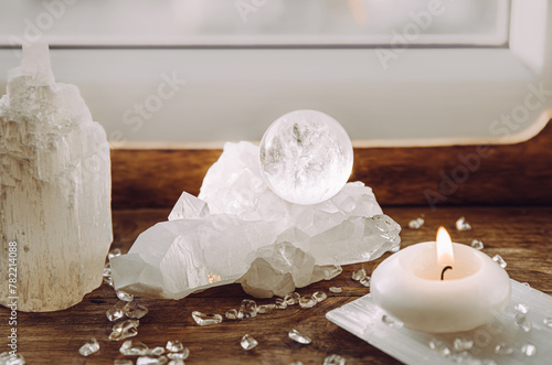 Gemstone sphere or crystal ball on quartz geode on wood tray, candle burning. Tranquil home concept. photo