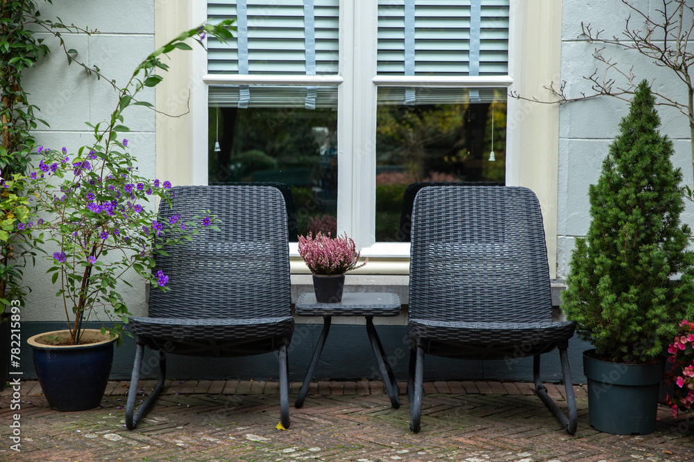 two garden chairs with flowers in front of window in a garden, lifestyle