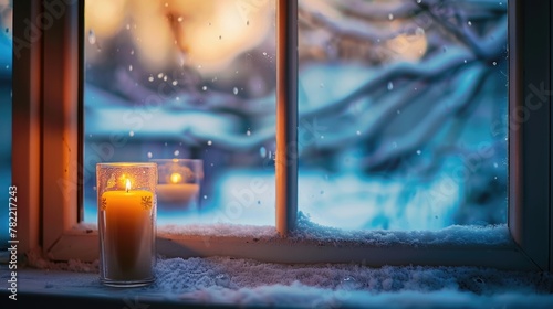 A lit candle on a window sill in the snow. Perfect for winter and cozy home concepts photo