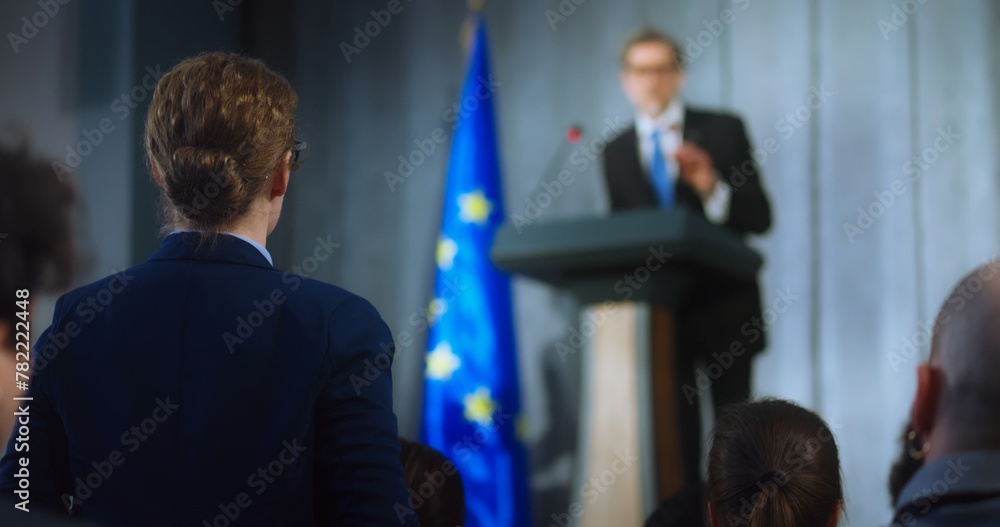 Obraz premium Female representative of media asks question to European politician performing at press conference. Confident EU consul makes an announcement, delivers campaign speech, gives interview. Election day.