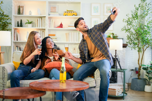 Photography Friends capturing a joyful selfie moment with champagne, sharing laughter in a vibrant, homey living room