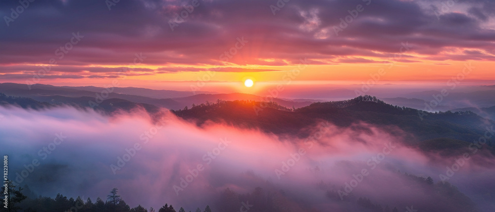 A vibrant sunrise illuminates misty mountain landscape, casting a dramatic and picturesque scene for all.