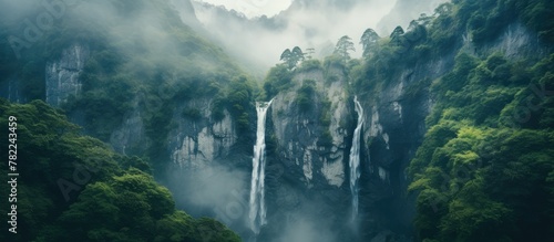 Waterfall cascading down a misty mountain amid lush forest