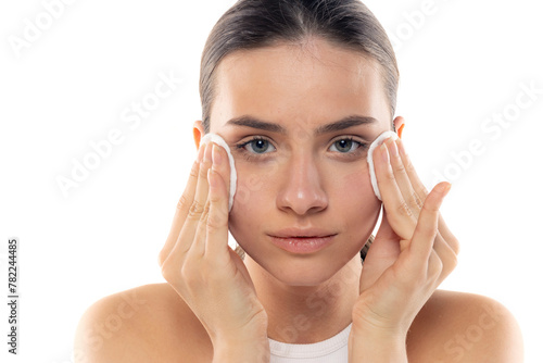 Portrait of a young woman removing her make-up on a white background