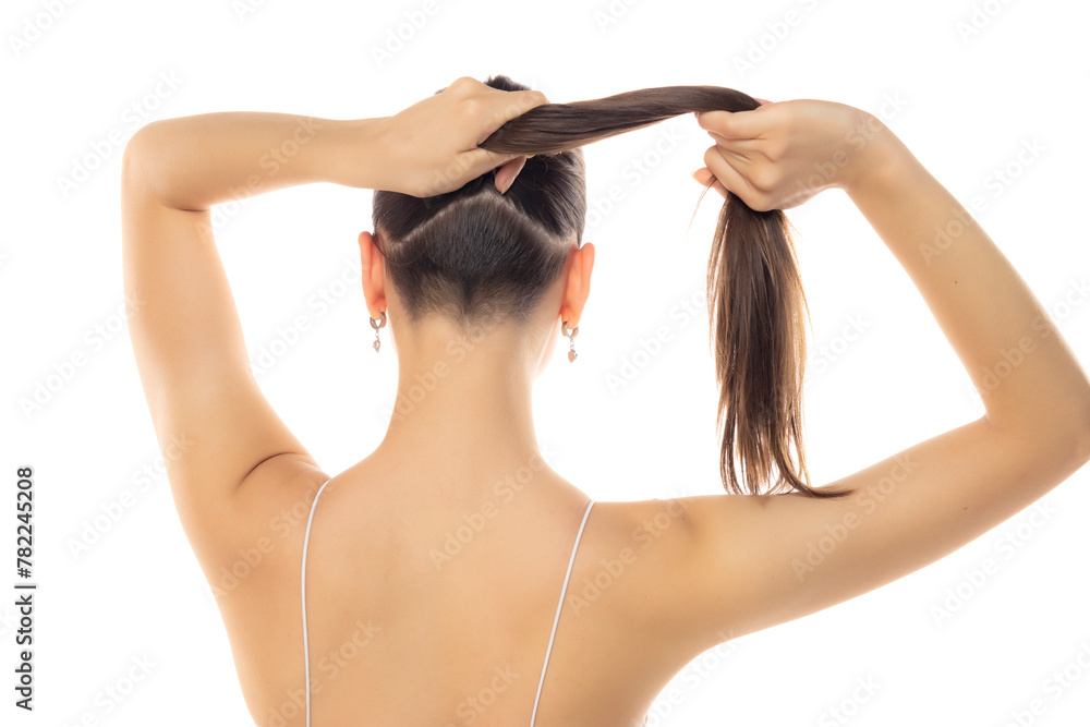 Obraz premium Rear view of a young modern woman with partially shaved head and ponytail on a white background