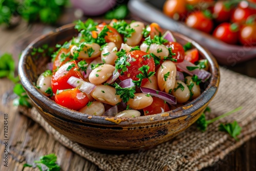 White bean salad with cherry tomatoes onion and parsley on wood background