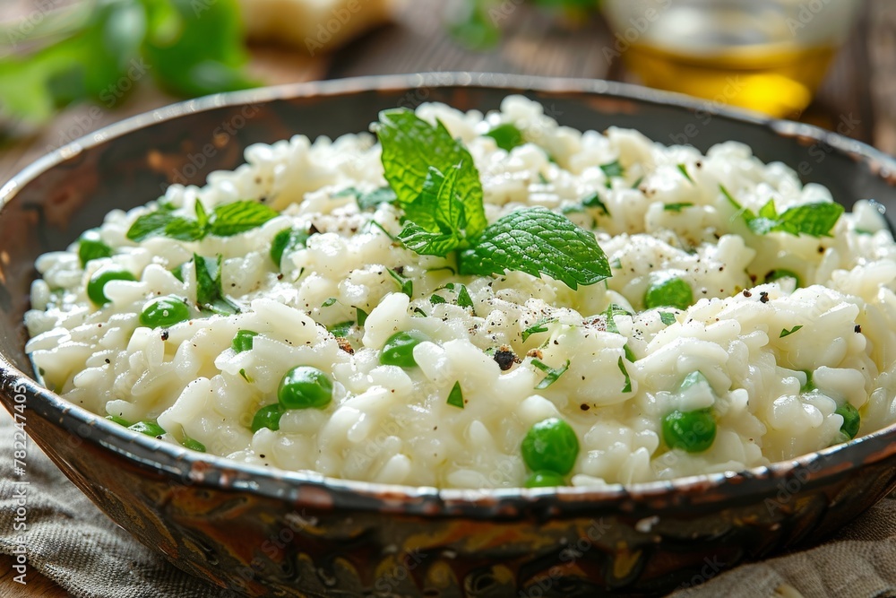 Creamy pea risotto sprinkled with grated cheese and garnished with a fresh mint leaf, served in an earthenware bowl. Creamy pea risotto sprinkled with grated cheese and garnished with a fresh mint leaf, served in an earthenware bowl.