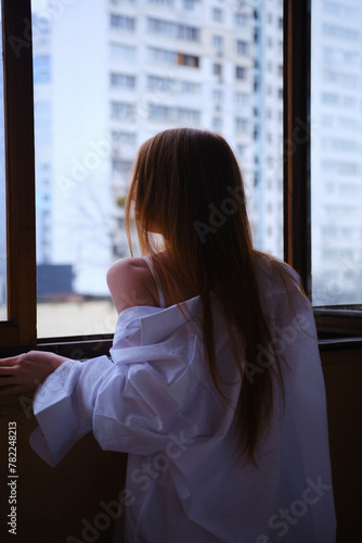 Young redhead Woman in white shirt Looks Out The Window on the balcony Deep In Thought red hairs ginger girl general plane