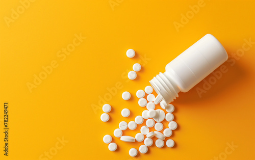 White pill bottle tipped over with pills scattered, yellow color background, top view - pill bottle, healthcare medication spill, pharmaceuticals medical supplies.