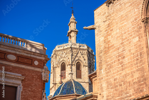 Valencia Cathedral's bell tower rises behind the old building of Ciutat Vella district on a sunny day