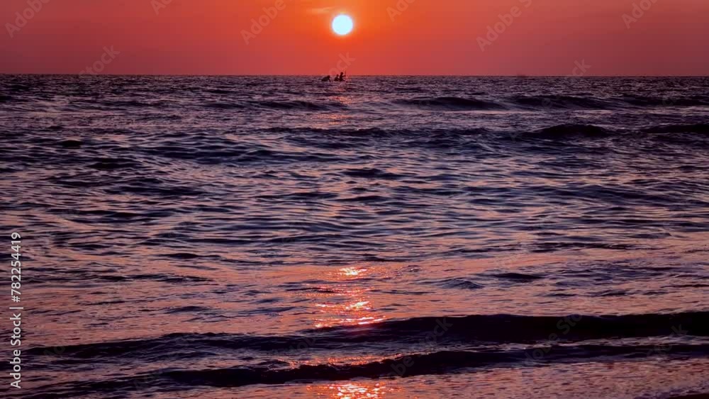 People enjoy canoeing on beach vacation during sunset