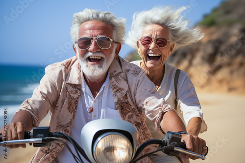 Joyful senior couple riding a scooter on beachside road