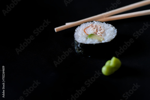 Maki présenté avec wasabi et baguette sur fond noir, cuisine japonaise et asiatique