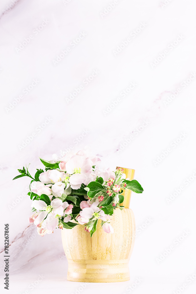 Wooden mortar with fresh aromatic apple flowers on white backgroundclose up. Natural herbal cosmetic banner.
