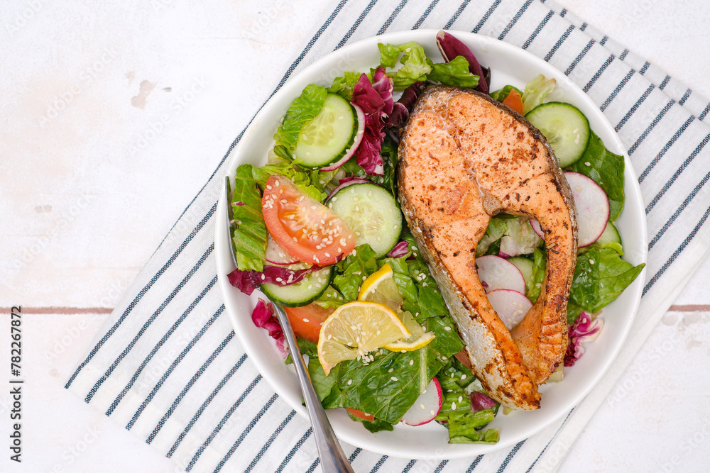 Grilled salmon and fresh vegetables: tomatoes, cucumber, lemon, radish on stripe napkin background. Grilled salmon and fresh vegetables: tomatoes, cucumber, lemon, radish on stripe napkin background.
