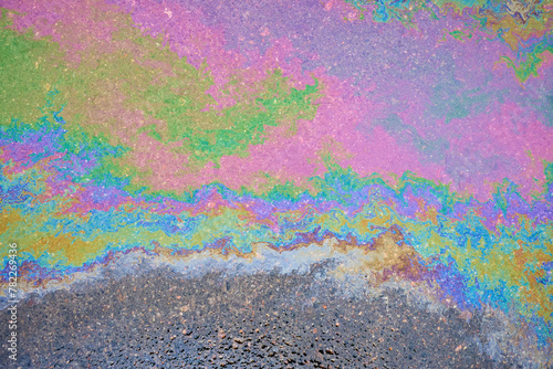 Oil stains from leaks in the car engine. Oil after rain makes spots with rainbow reflections refractive sun spectrum. Beautiful color mosaic, abstraction, ecology