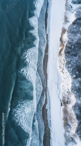 Aerial view of a snowy coastline with waves