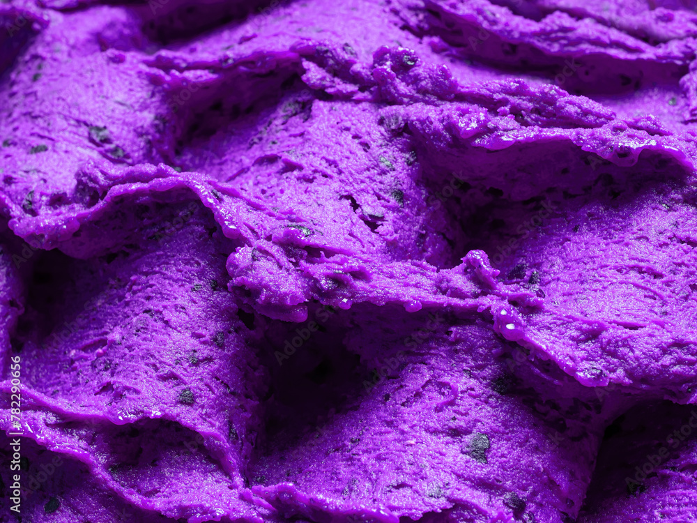 Frozen Lavender flavour gelato - full frame detail of sorbet. Close up of a violet surface texture of Ice cream filled with pieces of mixed flowers.