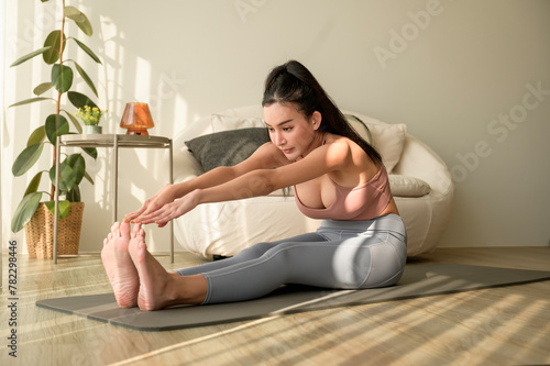 Asian woman in sportswear exercising and doing yoga in living room at home, healthy lifestyle, Mental health concept.