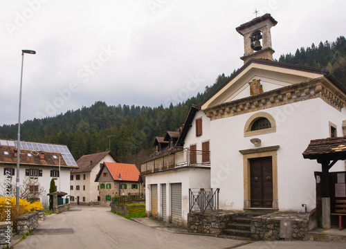A quiet residential road in the village of Ovaro in Carnia, Udine Province, Friuli-Venezia Giulia, north east Italy. The Gleseuta di Santa Taresia or Oratorio di Santa Teresa Church is on the right