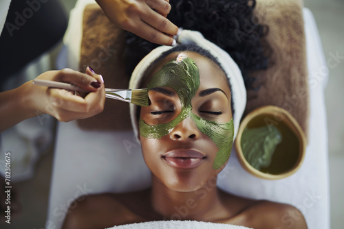 An ethnic African woman lying in a beauty salon receiving a natural herbal facial treatment. Beauty, natural and personal care treatment.