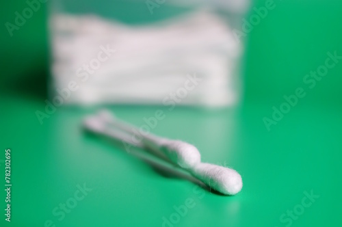 A cotton swab for ears on a green background. Body care and hygiene.