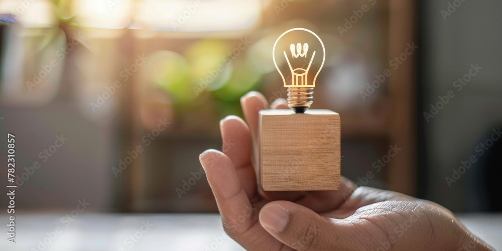 Obraz premium Hand holding a wooden block with a light bulb, concept of idea, creativity.