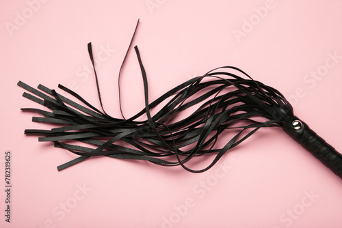 Leather bdsm whip on pink background. Erotic toys for BDSM