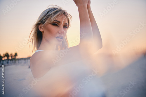 Woman raises her arms in an expression of freedom with a soft-focus sunset catalyzing the visual effect