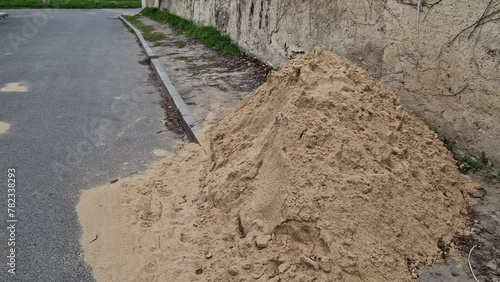 on the street lies a folded pile of sand or red clay. repair of the road of the house backfill gas power line, or reconstruction of the tennis court playground, bricklayer photo