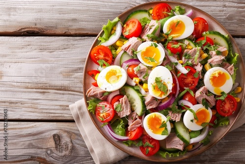 Close up top view of gourmet nicoise salad with vegetables eggs tuna and anchovies on a plate