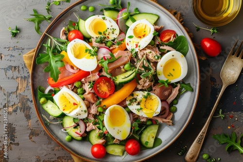 Close up top view of gourmet Nicoise salad with vegetables eggs tuna and anchovies on a table plate