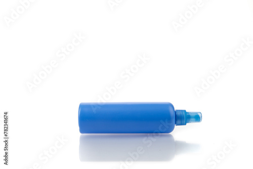 A generic blue plastic hair product or cleaning solution spray bottle with pump sprayer on white with reflection on table