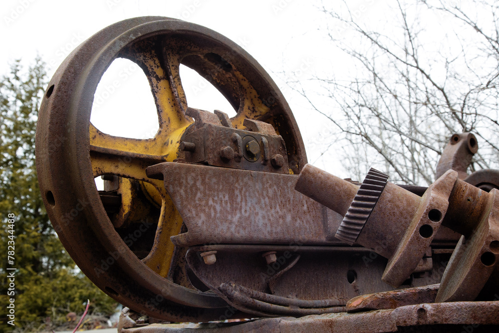 A rusty scrap machinery flywheel in a field