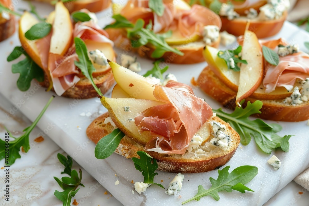 Delicious appetizers on white marble board with pear prosciutto arugula and blue cheese Delicious appetizers on white marble board with pear prosciutto arugula and blue cheese