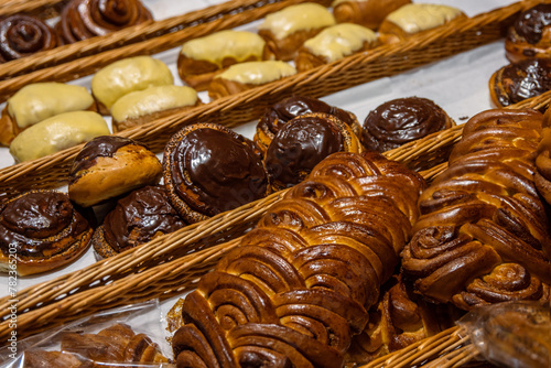 A lot of sweet pastries in baskets on the counter in the food store. Bakery on the buffet table. Business breakfasts and catering at events. Various bread type on shelf. Close-up. Selective focus.