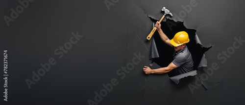 A fearless construction worker with a yellow helmet smashing through a dark barrier with a hammer, symbolizing breakthrough and determination photo