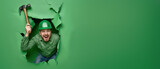 A happy construction worker in green swinging a hammer inside a paper tear