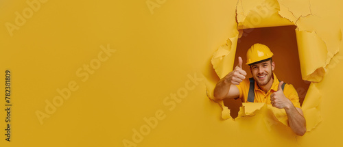 A cheerful construction worker gives a thumbs up through a yellow tear, embodying job satisfaction photo
