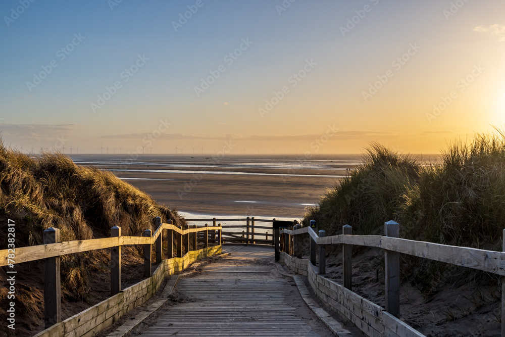 A walkway leading to the beach, with a sunset sky overhead