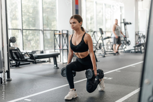 fit woman does dumbbell squats in fitness gym