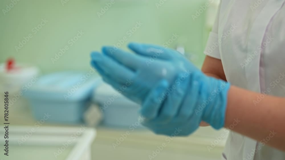 Close-up hands of unrecognizable woman nurse using antibacterial sanitizer on medical gloves at modern clinic. Concept of antiseptic disinfection, sterile work, infection protection, slow motion. Close-up hands of unrecognizable woman nurse using antibacterial sanitizer on medical gloves at modern clinic. Concept of antiseptic disinfection, sterile work, infection protection, slow motion.