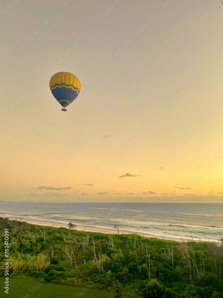 Obraz premium Hot air balloon in the morning sky across Australia, with the coast and rolling sea in the background